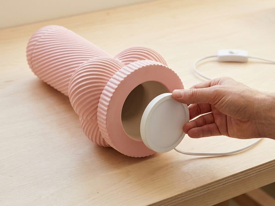 La Lampe Monsieur couchée, socle vers l'objectif : le corps est creux, et une main vient boucher l'ouverture avec le disque LED blanc, pile à sa taille