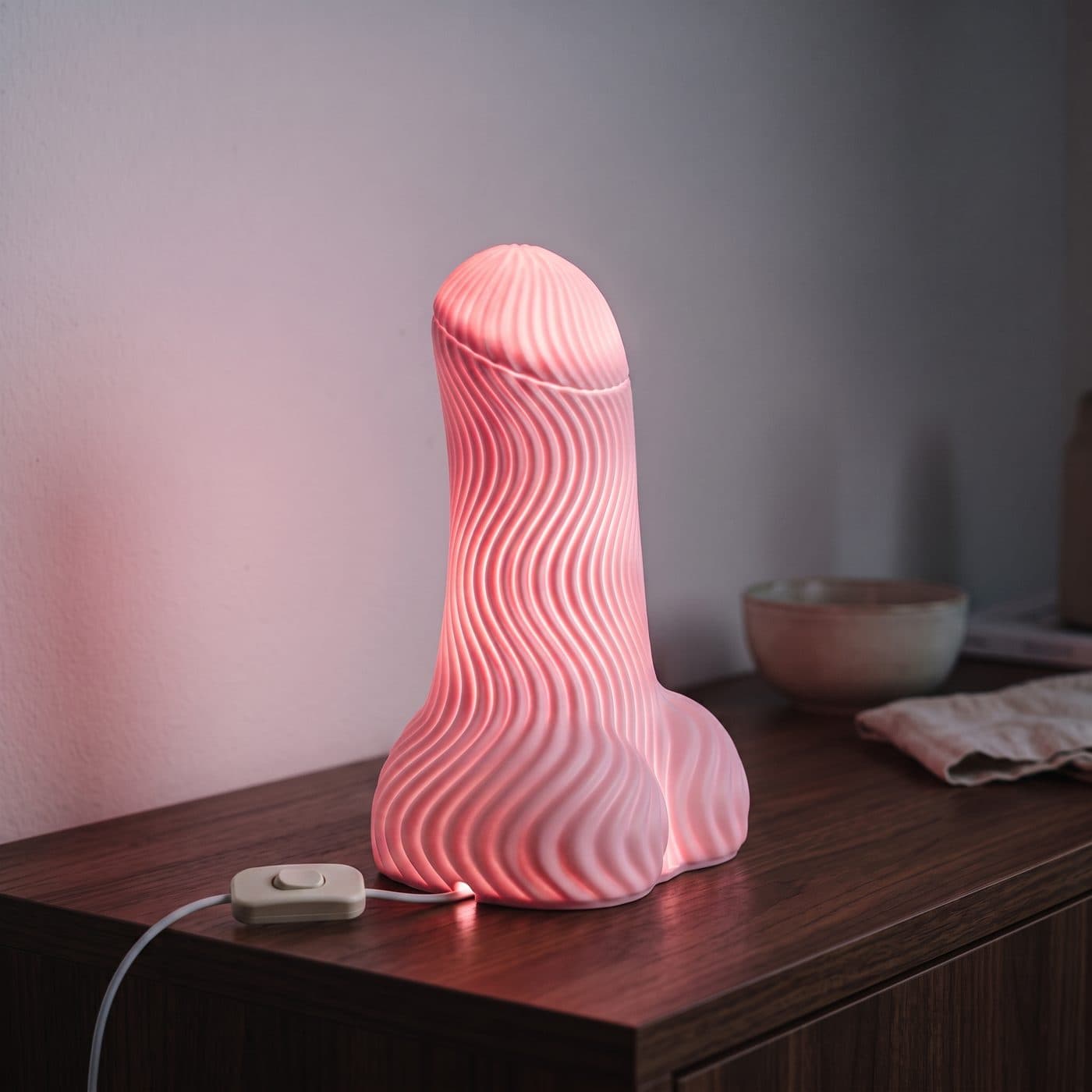 Lampe à poser originale Lampe Semence allumée dans le noir sur une console en noyer, interrupteur sur le fil